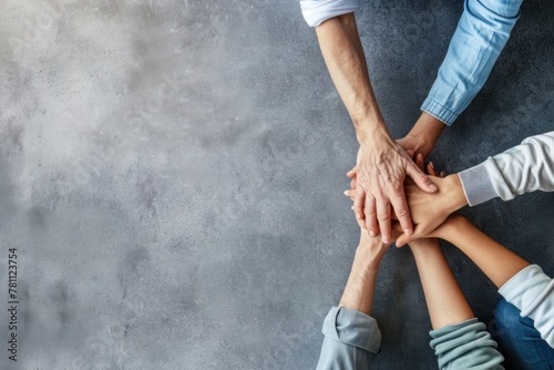 High angle view of business people holding each other's hands on a grey background with copy space