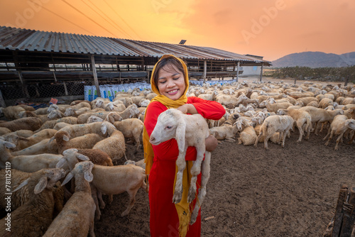 Vietnamese woman with lamb on a countryside, a sheep farm in the steppe zone in Ninh Thuan Province, Vietnam. © CravenA