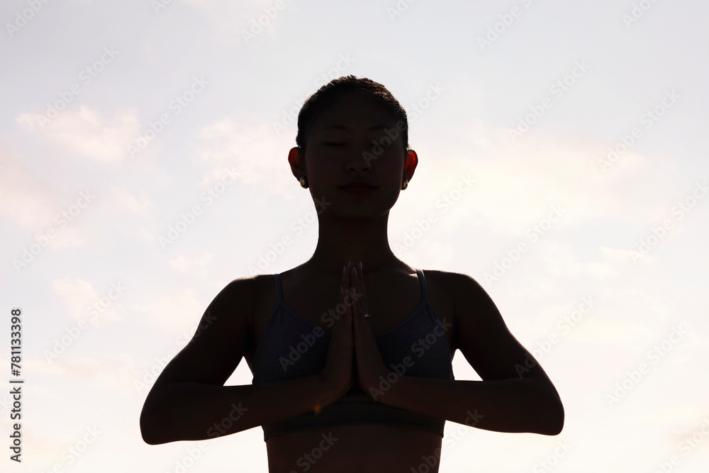 backlight portrait of young woman practicing yoga in pray position, concept of mental relaxation and healthy lifestyle, copy space for text backlight portrait of young woman practicing yoga in pray position, concept of mental relaxation and healthy lifestyle, copy space for text