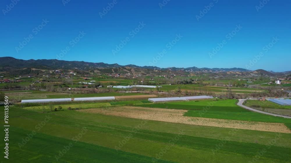 Rural Landscape with Green Parcels, Greenhouses, and Cultivated Land in Spring: Agriculture Flourishing in a Beautiful Valley in Albania Rural Landscape with Green Parcels, Greenhouses, and Cultivated Land in Spring: Agriculture Flourishing in a Beautiful Valley in Albania
