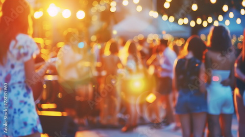 Blurred people at summer music festival party with bokeh lights