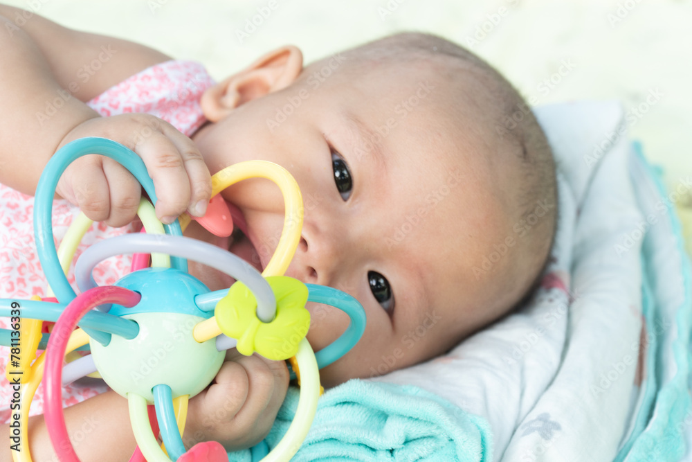 Esther Title: Infant Baby Girl is laying on her back in a pink bodysuit with a development toy for teething. Esther Title: Infant Baby Girl is laying on her back in a pink bodysuit with a development toy for teething.