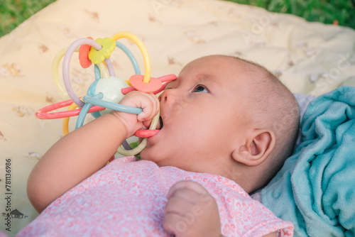 Esther Title: Infant Baby Girl is laying on her back in a pink bodysuit with a development toy for teething.