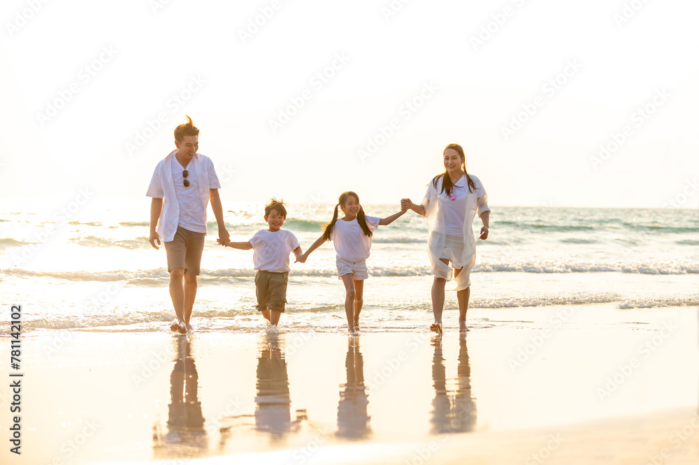 Happy Asian family travel nature ocean on summer holiday vacation. Parents and little child kid enjoy and fun outdoor activity lifestyle walking and playing together on tropical island beach at sunset