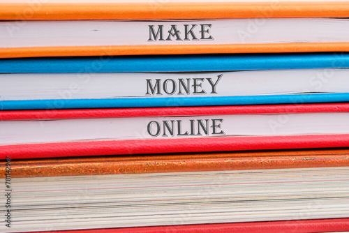 Business concept. MAKE MONEY ONLINE lettering written on notebooks stacked in a pile