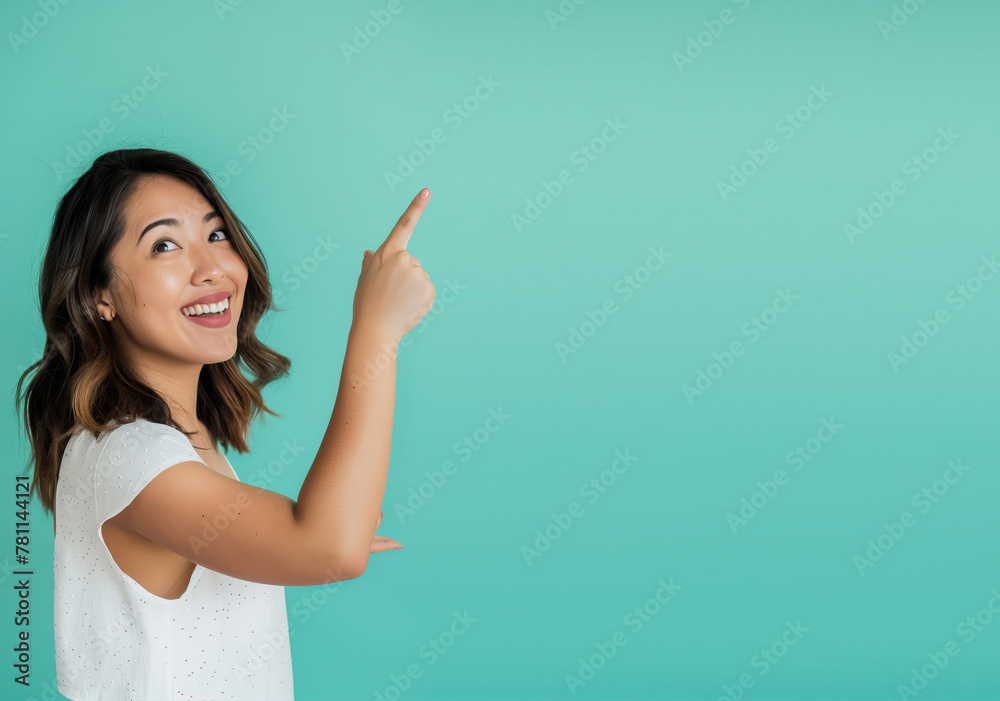 Smiling woman on mint background points her hand to the side
Smiling woman on mint background points her hand to the side