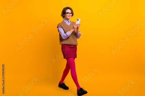 Photo portrait of attractive young woman walk hold telephone dressed retro office clothes isolated on yellow color background