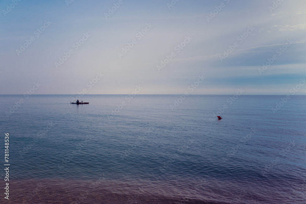 Sea, calm, a lonely fisherman's boat near the shore and a red buoy