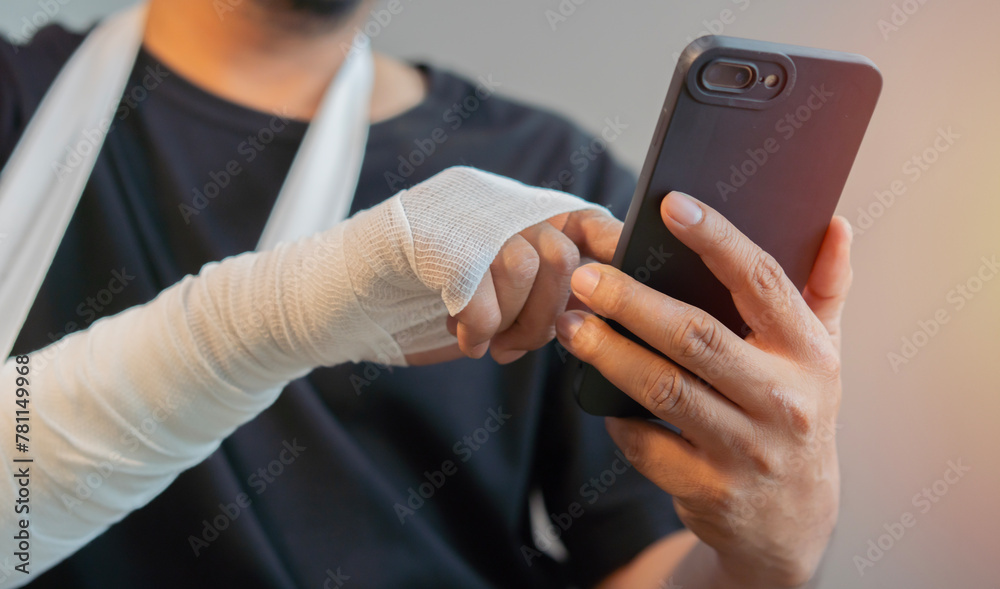 Man with gauze bandage or plaster cast on broken hand, broken wrist use smart phone.