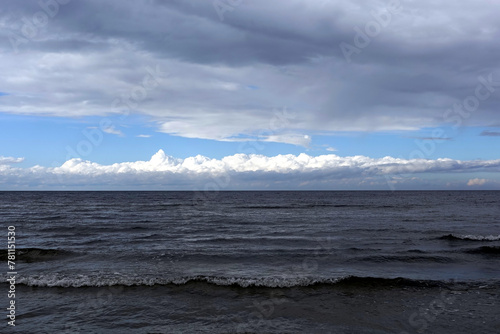 Dark cold waves of the Baltic Sea with layer of white clouds on skyline on a overcast windy day