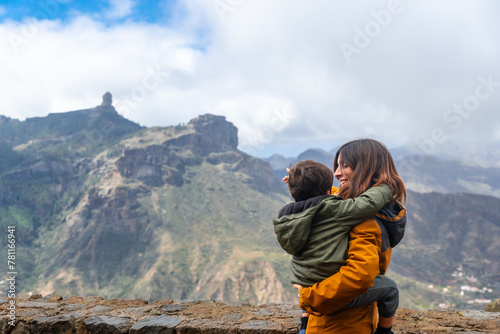 A mother with her son looking at Roque Nublo from a viewpoint. Gran Canaria, Spain