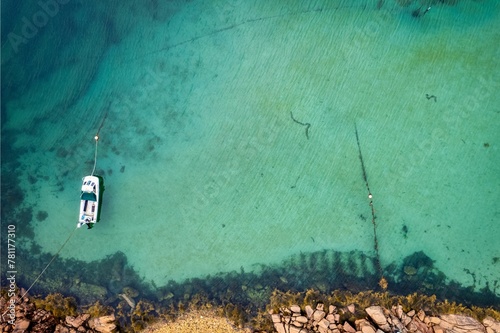 Aerial top view of a boat docked on the water by a coast in Donegal