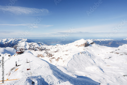 Breathtaking view of Murren ski resort, Switzerland, with snow covered peaks and ski lift. Well maintained terrain for winter sports under clear blue sky.