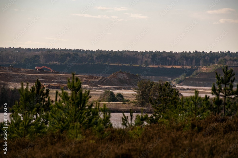 Bulldozer mining a landscape for raw materials against pine forests