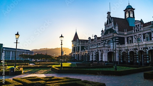 Foto Beautiful Dunedin Railway Station with the golden sunset behind the hill in the