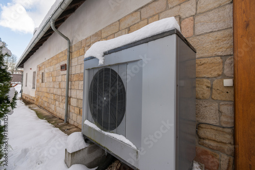 Air heat pump beside an old country house in winter