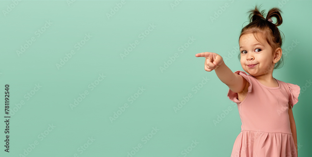 A little girl on a turquoise background points her finger to the side. Free space for text.
A little girl on a turquoise background points her finger to the side. Free space for text.
