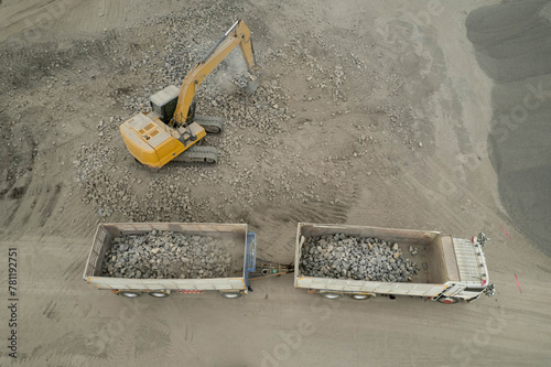 excavator scooping rocks, stone construction