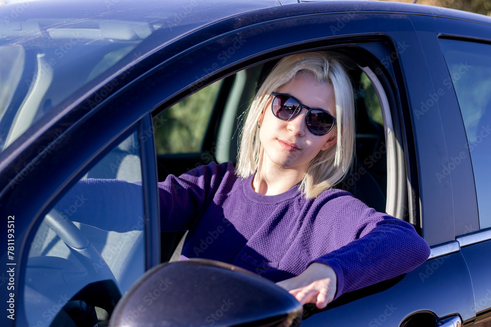 Blonde in sunglasses relaxed at car wheel
