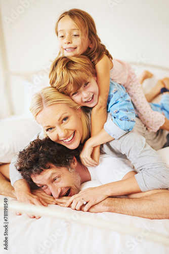 Portrait, happy and family on bed with kids, parents and play for bonding in bedroom. Couple, children and smiles for together, love and support in home on weekend for relaxing, break and happiness © peopleimages.com