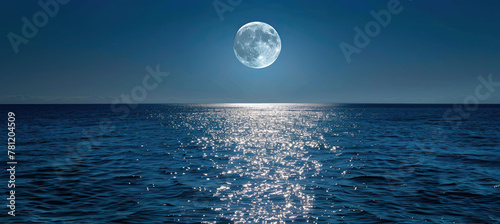 full moon rising over a calm ocean  casting a path of shimmering silver on the water surface. 