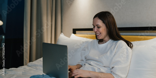 Happy Woman Using Laptop in Comfortable Bedroom.