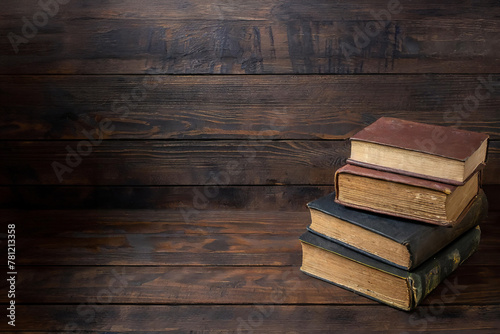 Four old books leather binding stack on top of each other dark background wood beams antique empty space