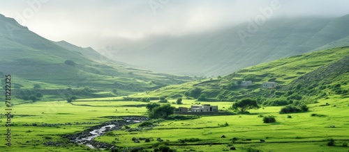 House by stream in valley, distant green Salalah landscape photo