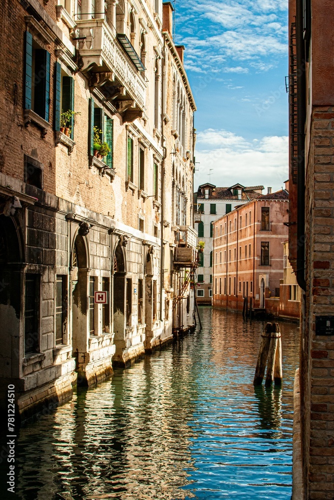 Vertical shot of a water canal flowing between traditional houses in Venice