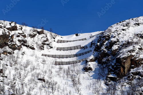 Avalance fences on top of a hill above small city of Øksfjord in Finnmark in Northern Norway on sunny march afternoon in 2024. photo