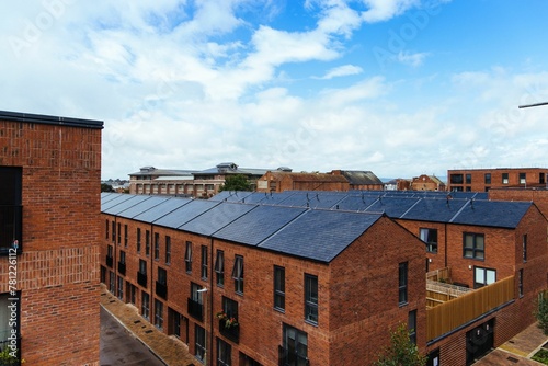 View of red brick buildings under a blue sky with clouds.