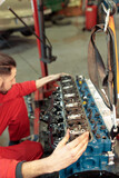 Vertical shot of a young Caucasian mechanic mounting the car engine