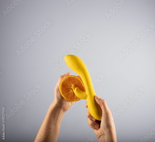 Female hand holding the sex toy and the orange
