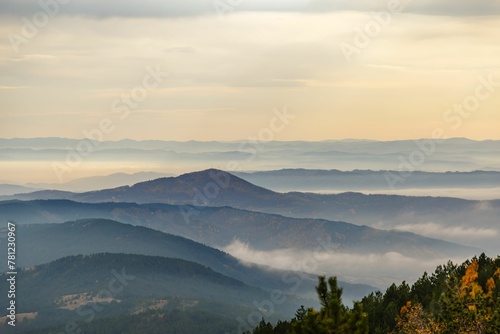 Aerial view of a range of mountains covered in fog at sunset with a cloudy sky in the background
