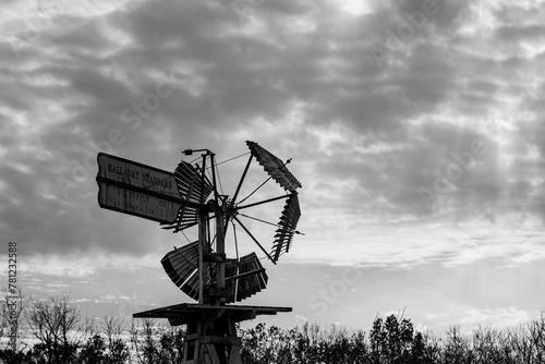 Grayscale shot of an old handmade wooden dempster vaneless windmill on a cloudy day