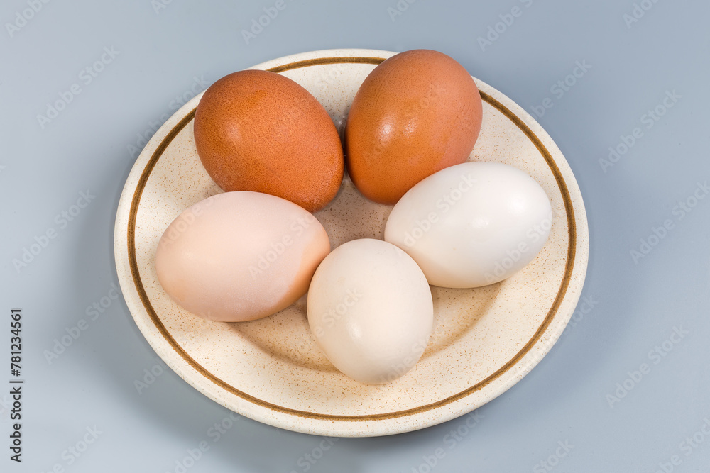 Whole boiled chicken eggs different colors on a saucer
