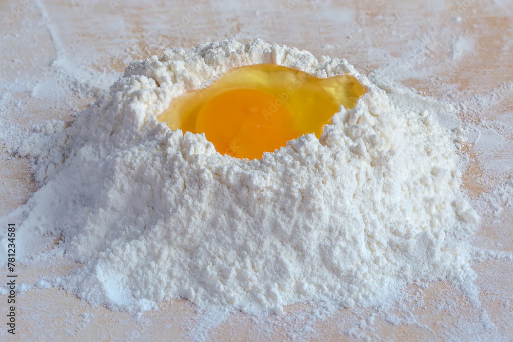 Broken egg on a heap of wheat flour close-up Broken egg on a heap of wheat flour close-up