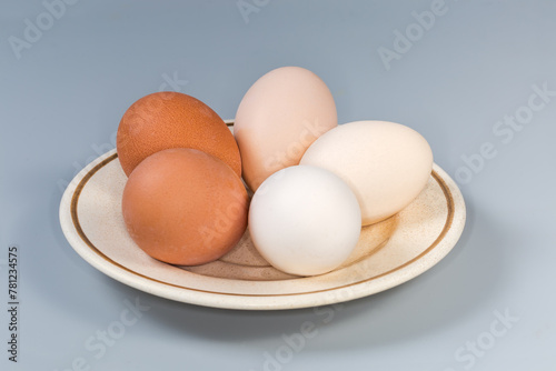 Whole boiled chicken eggs different colors on saucer, side view