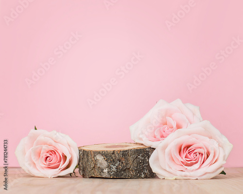 Wooden sawcut platform with pink roses. Round wooden saw cut cylinder shape for product presentation on a pink background, eco style. Wood slice mockup.