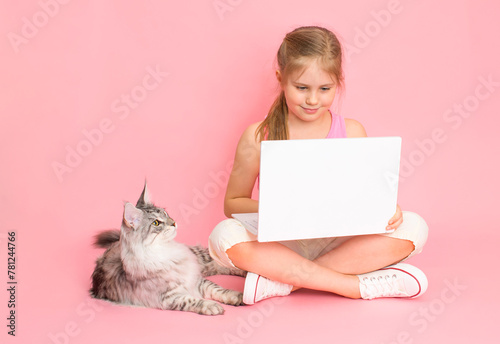 Little girl with laptop and cat over pink background.