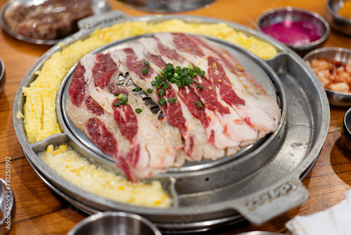 Korean barbecue restaurant, the waiter lays a barbecue net on the red environmentally friendly barbecue charcoal and uses food tongs to place strips of beef belly. A tutorial on cooking delicious  photo