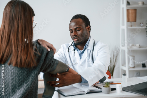 A doctor measures a young woman's blood pressure