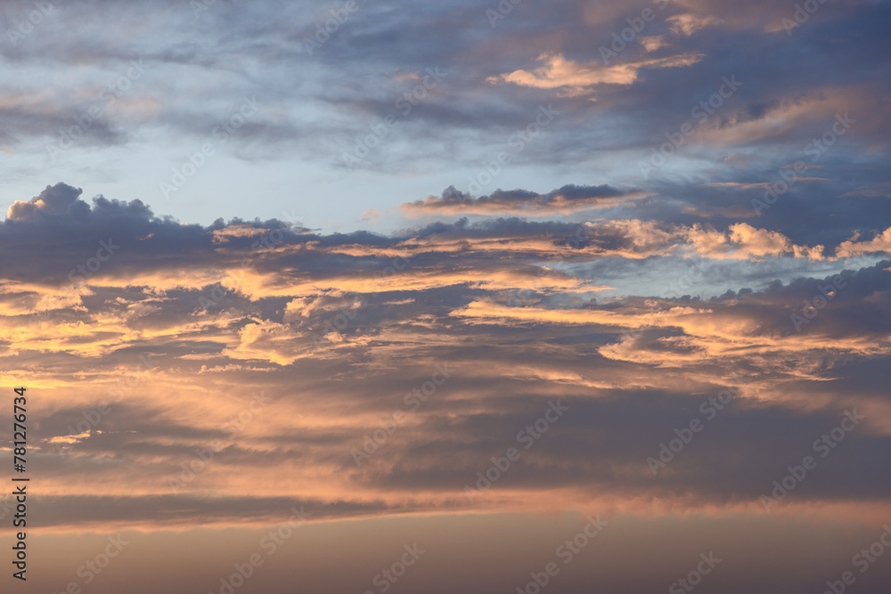 Layered clouds at sunset display a rich tapestry of gold and lavender hues, offering a majestic backdrop perfect for artistic endeavors and sky replacements