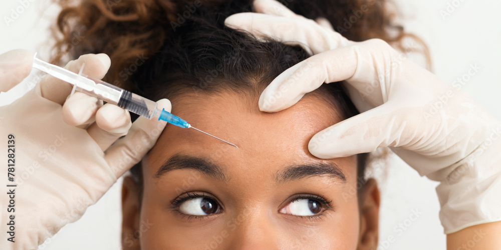 African-american woman getting botox injection in forehead African-american woman getting botox injection in forehead