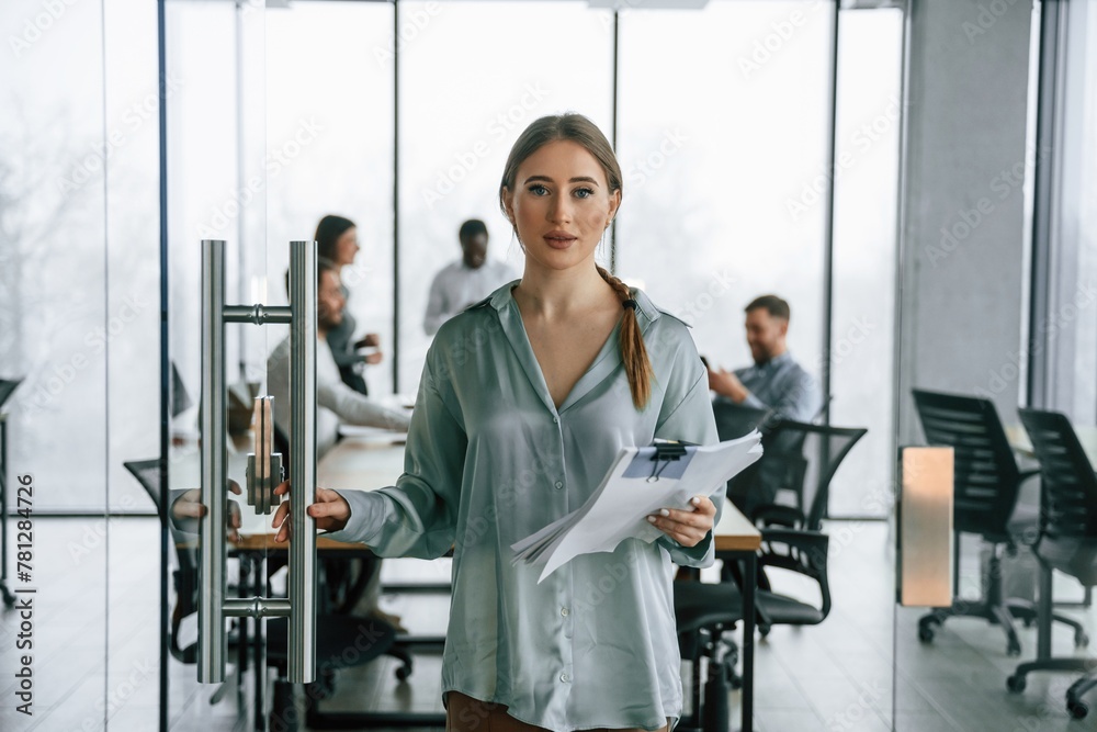 Female manager is with documents. Team of office workers are together indoors Female manager is with documents. Team of office workers are together indoors