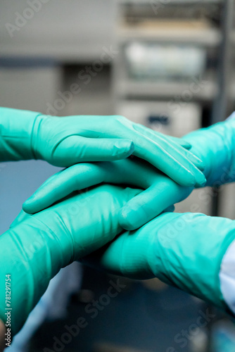 close-up of clasped hands of doctors wearing green gloves together before surgery