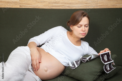 Expectant mother looking at sonograms on couch
