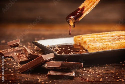 Fresh Churros with chocolate dipping sauce on wood background