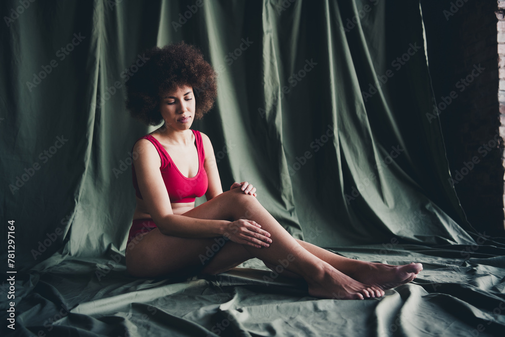 Unretouched photo of girl sit touch skin legs isolated khaki linen background Unretouched photo of girl sit touch skin legs isolated khaki linen background