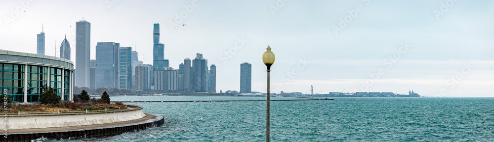 Fototapeta premium The Shedd Aquarium in Chicago stands against the backdrop of the city's shoreline along Lake Michigan, with a misty skyline.
